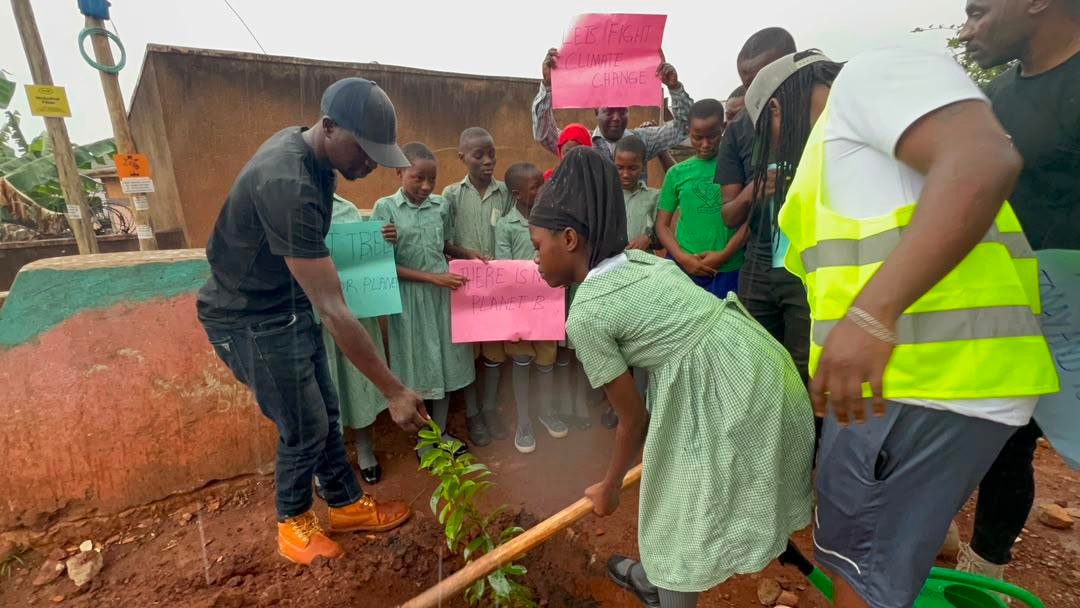 Schoolchildren holding climate change awareness signs during tree planting activity